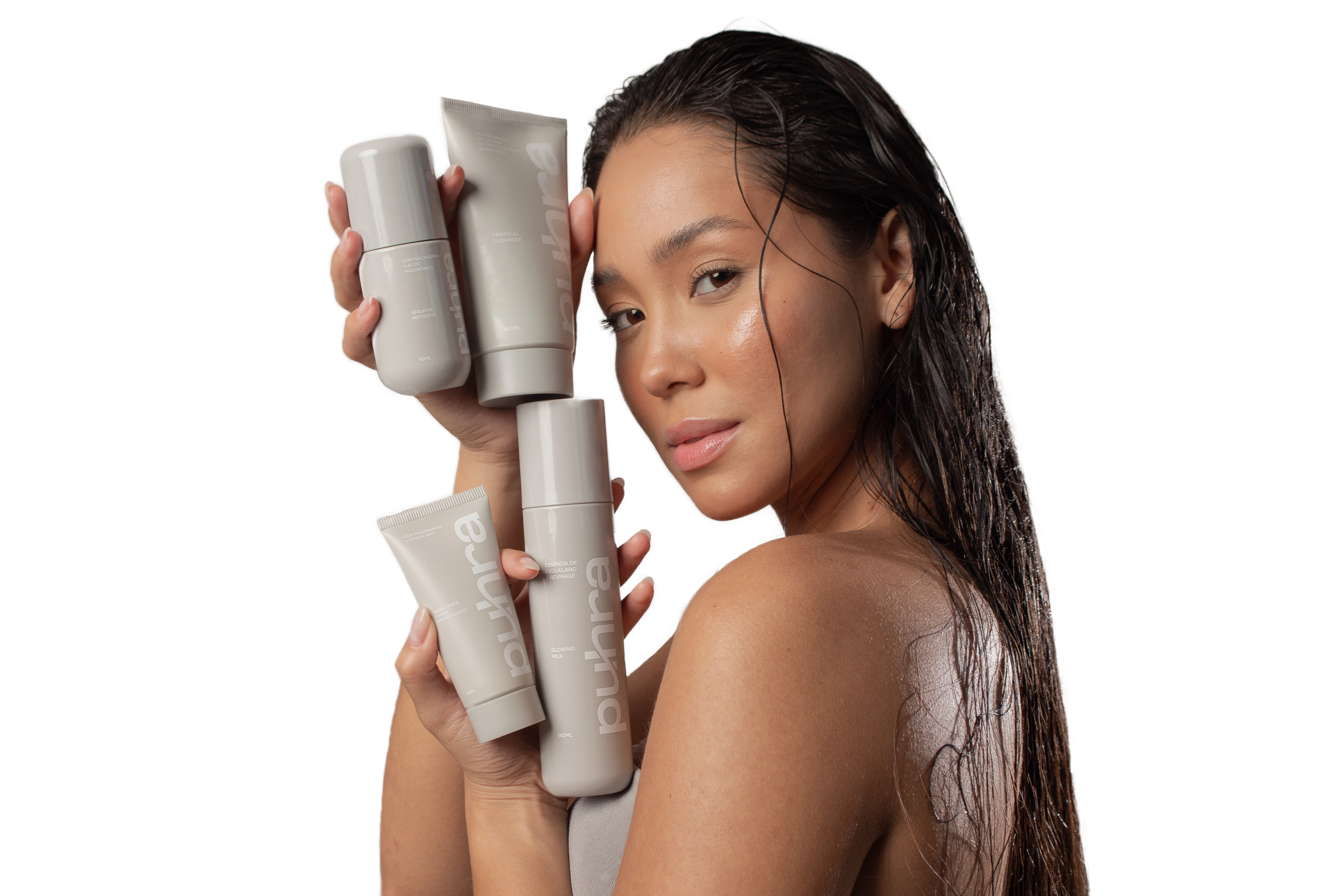 Imagem de uma modelo segurando quatro frascos de produtos, com um fundo neutro e iluminação suave, transmitindo uma sensação de elegância e sofisticação